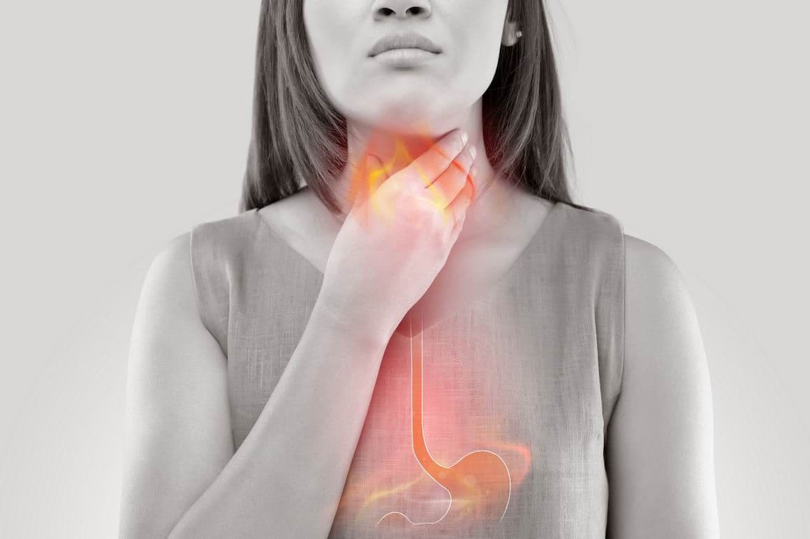 Femeie care suferă de iritație în gât cauzată de refluxul gastroesofagian – simptom frecvent al laringitei de reflux.