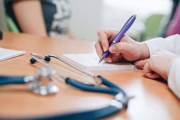 Doctor scriind o rețetă sau oferind recomandări unui pacient, explicând opțiunile de tratament, complicații