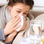 Femeie răcită acasă, învelită într-o pătură, tratându-se singură fără consult medical