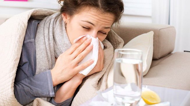 Femeie răcită acasă, învelită într-o pătură, tratându-se singură fără consult medical